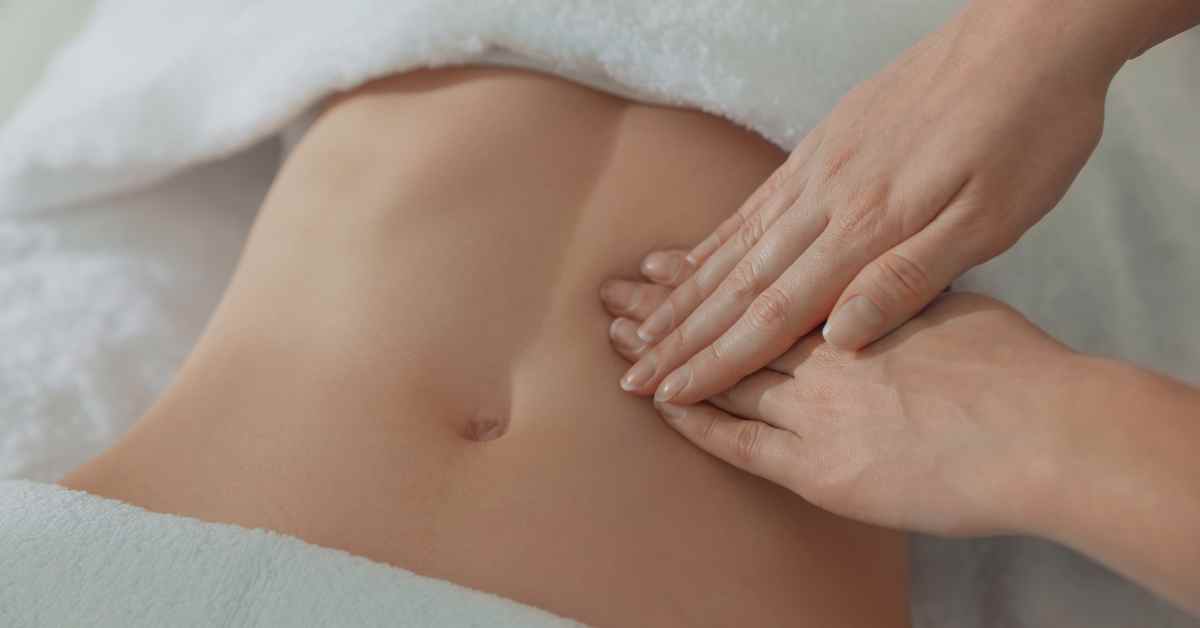 Close-up of a therapist performing lymphatic drainage massage on the abdominal area, demonstrating a technique that may help reduce swelling but can also cause mild lymphatic drainage side effects.