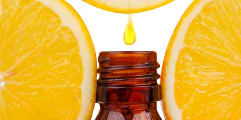Fragrance oil vs essential oil – drop of orange oil with fresh orange slices in the background